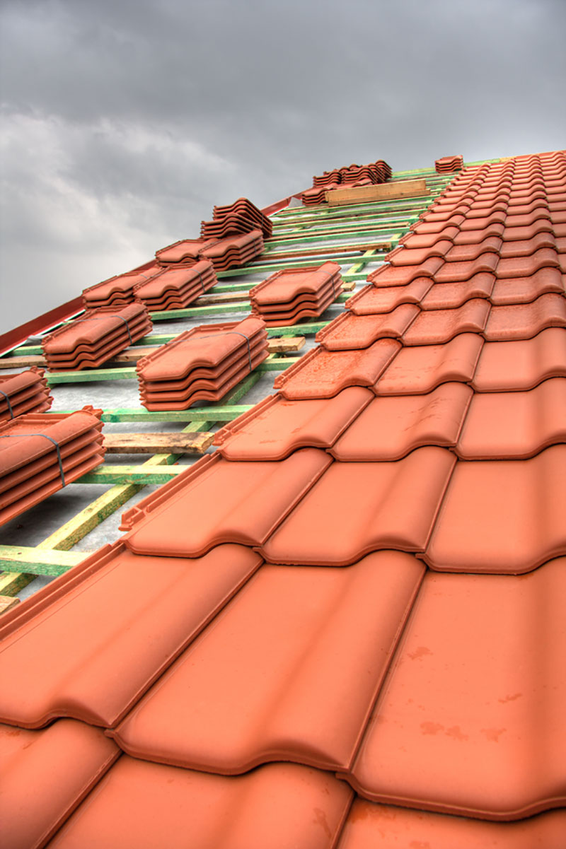 Vue rapprochée d’une toiture en cours de rénovation à Franconville, mettant en évidence des tuiles rouges récemment posées sur une charpente robuste. Ce chantier de couverture illustre le savoir-faire d’un artisan couvreur spécialisé dans les travaux de toiture, alliant esthétique et durabilité.